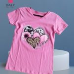 Polo infantil para niña de color rosa con estampado de corazones y flor en algodón.